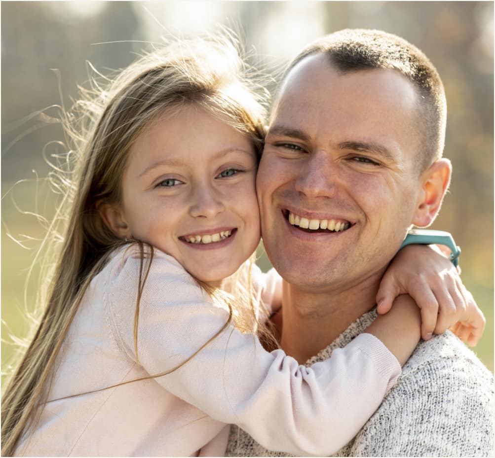 Father and daughter smiling together at family dental visit